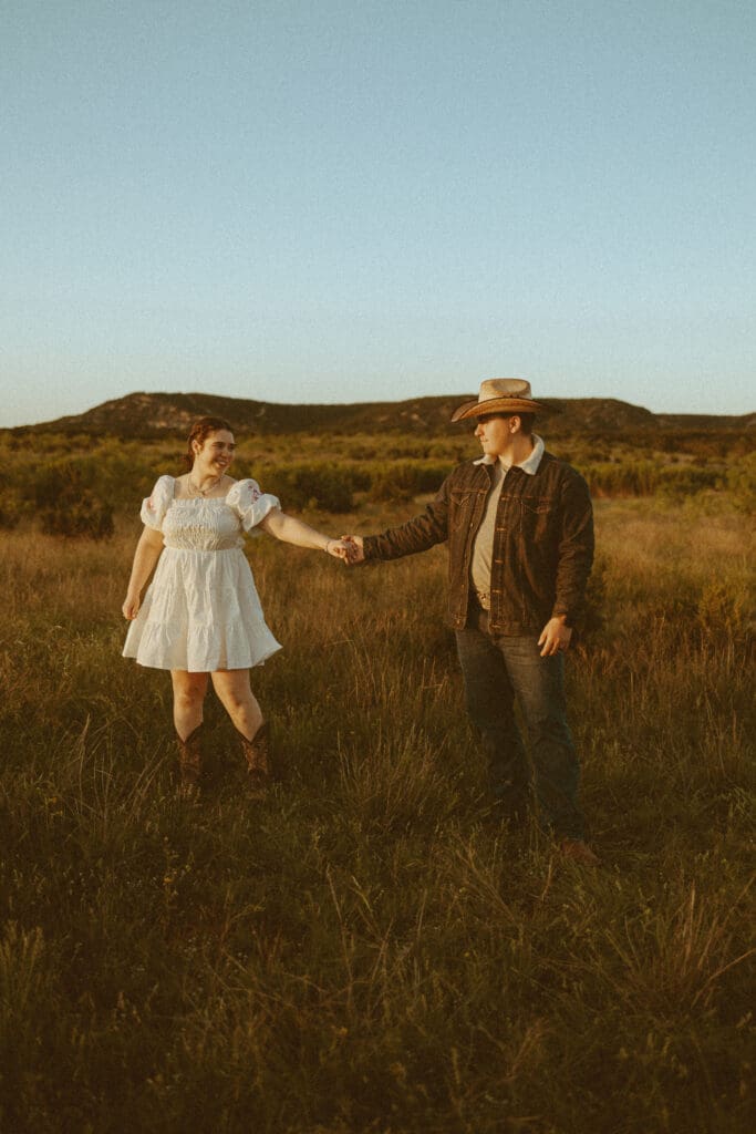 Playful and intimate golden hour couples session in a field at Barn at Cliff Spring in Abilene, TX