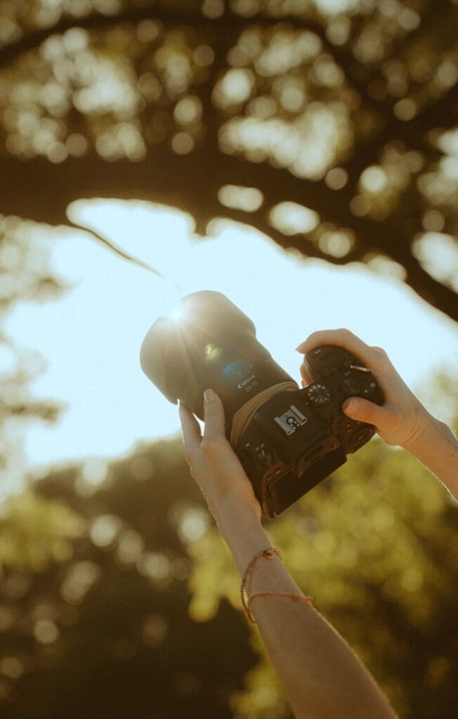 Warm golden hour detail photo of a photographer’s camera and hands, representing the care and preparation vendors put into each session.