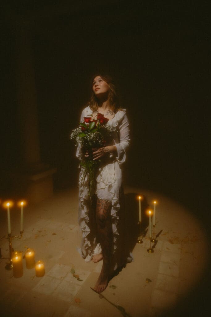 Cinematic portrait of a woman holding a bouquet of red roses in soft, dramatic lighting. Moody lifestyle photography with warm tones, nostalgic styling, and editorial-inspired shadows. Perfect example of creative portrait photography, fine art portraits, and golden-hour-inspired indoor lighting. Ideal for photographers showcasing emotional, artistic, storytelling portrait work.