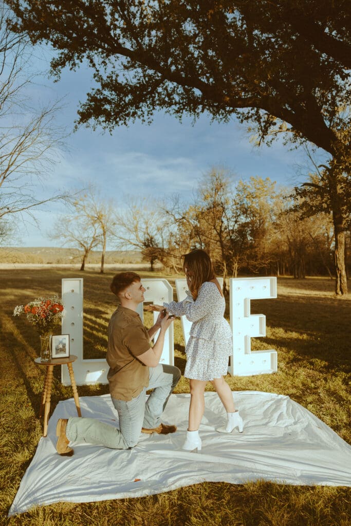 Romantic and surprise proposal with marque letters that say "LOVE" in a field in Buffalo Gap, TX