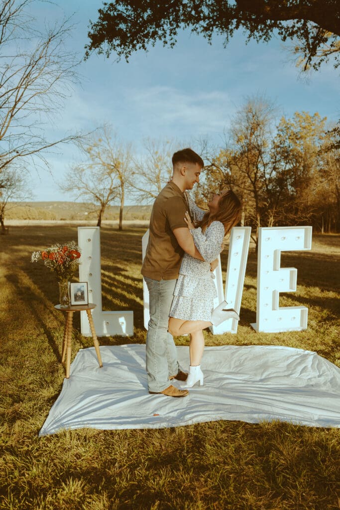 Romantic and surprise proposal with marque letters that say "LOVE" in a field in Buffalo Gap, TX
