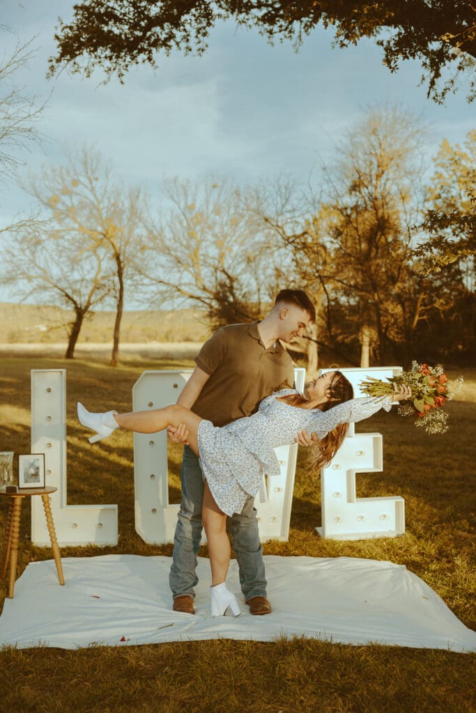 Romantic and surprise proposal with marque letters that say "LOVE" in a field in Buffalo Gap, TX