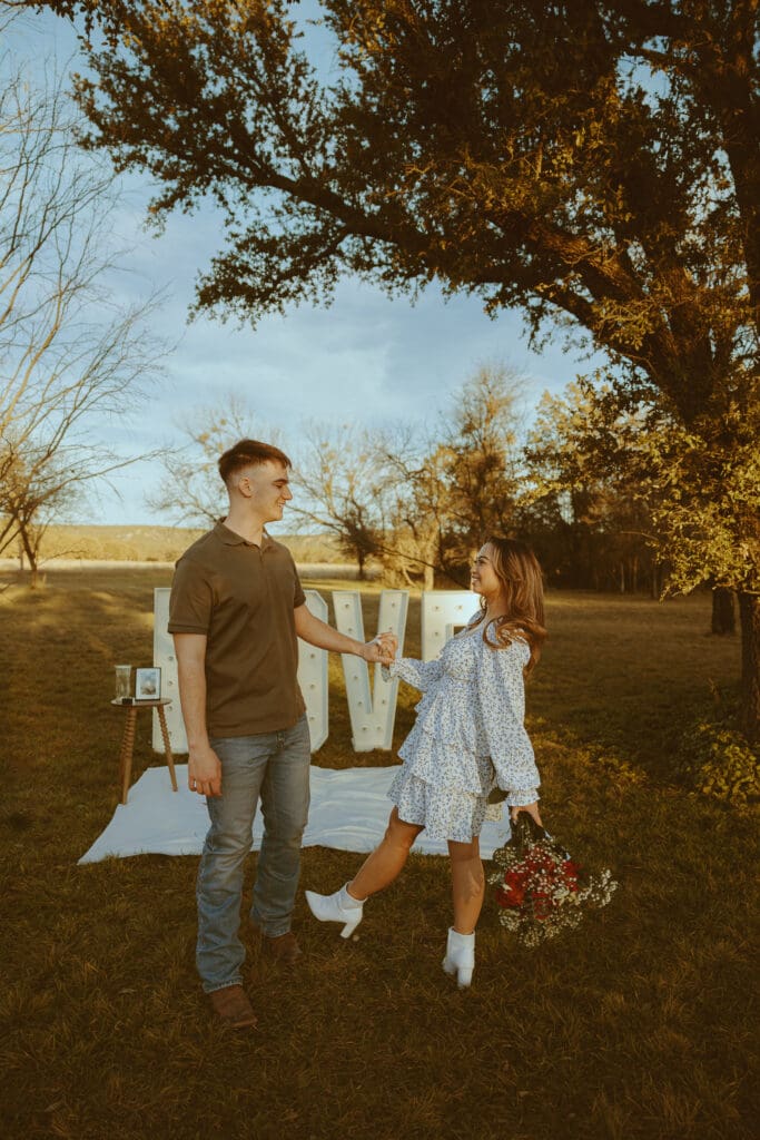 Romantic and surprise proposal with marque letters that say "LOVE" in a field in Buffalo Gap, TX