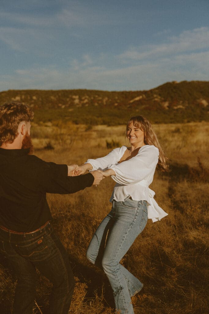 Couple wearing neutral outfits that photograph beautifully during a golden hour fall couples photo session on in a golden field in Abilene, TX