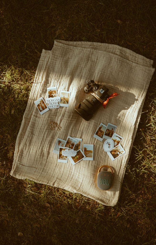Flat lay of photography branding materials by Morgan Rose Photography, featuring a camera, branded prints, and nostalgic business details styled outdoors in warm golden light.
