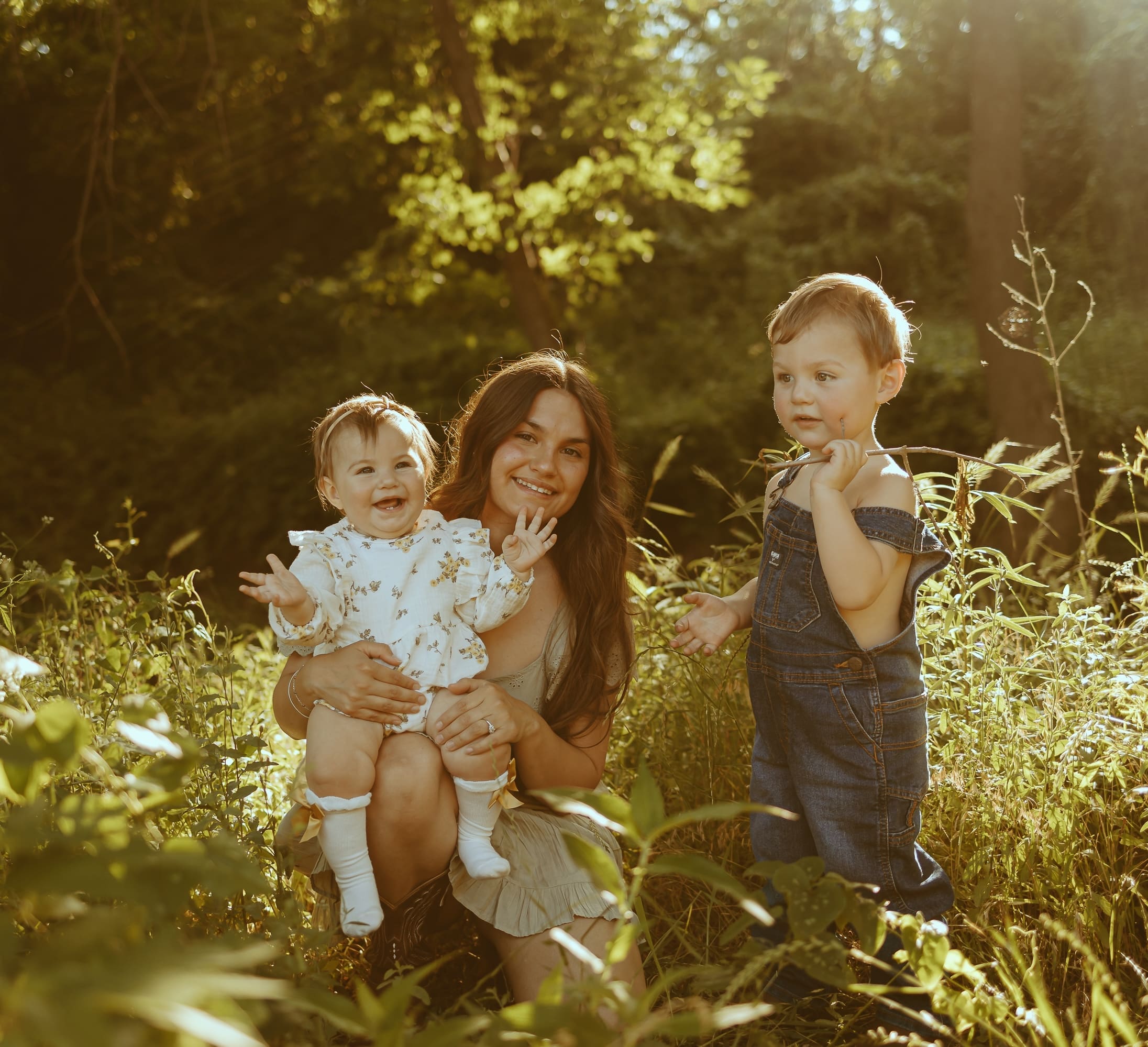 Mother holding her two young children in a sunlit open field during golden hour in Abilene, Texas. A warm and nostalgic motherhood photography session captured with natural light and candid emotion by Morgan Rose Photography.