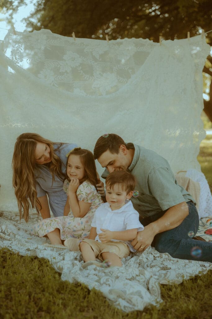 Family embracing together during golden hour in Abilene with warm dreamy light, soft movement, and nostalgic earthy tones. Emotional lifestyle family photography focused on connection and storytelling by Morgan Rose Photography.