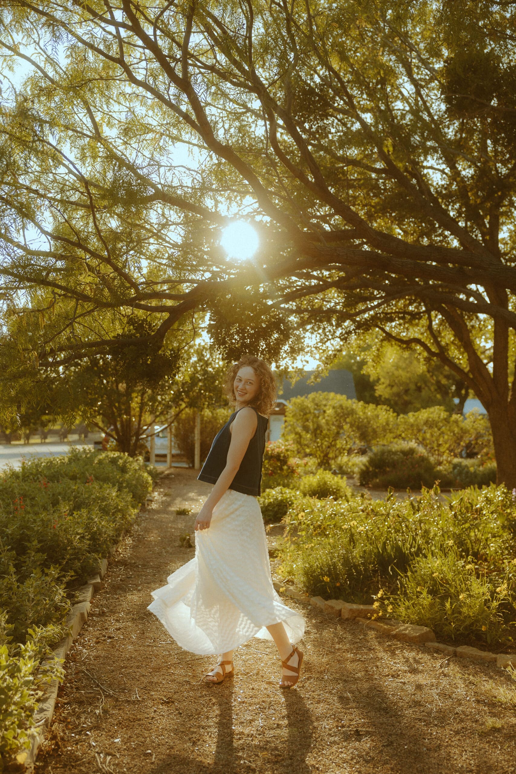 Senior portrait photographed during golden hour with warm sunlight filtering through trees in Abilene, Texas.