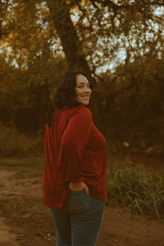 Senior posing outdoors among warm fall colors during a senior photography session in Abilene, Texas.