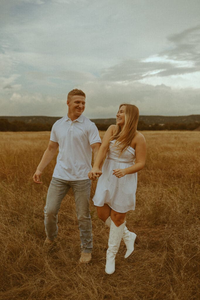 Couple walking hand in hand through a golden West Texas field during a fall photography session in Abilene, Texas.