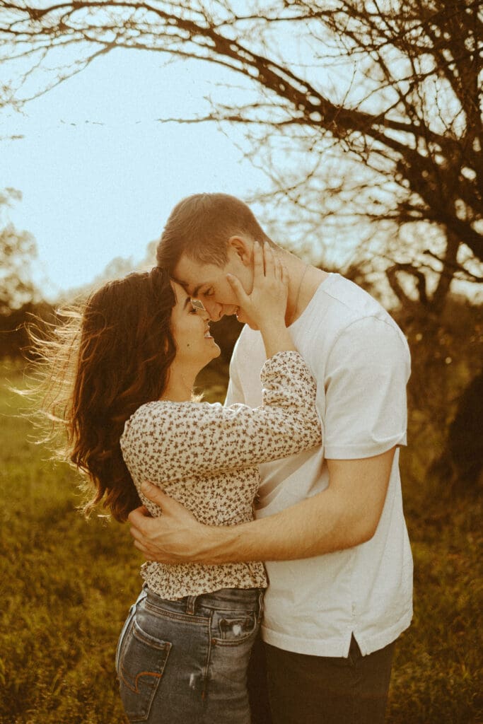 Couple embracing and touching foreheads during a golden hour photography session in Abilene, Texas, showing a natural pose for photos.